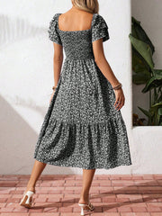 Black floral smocked midi dress with ruffle sleeves and tiered skirt.