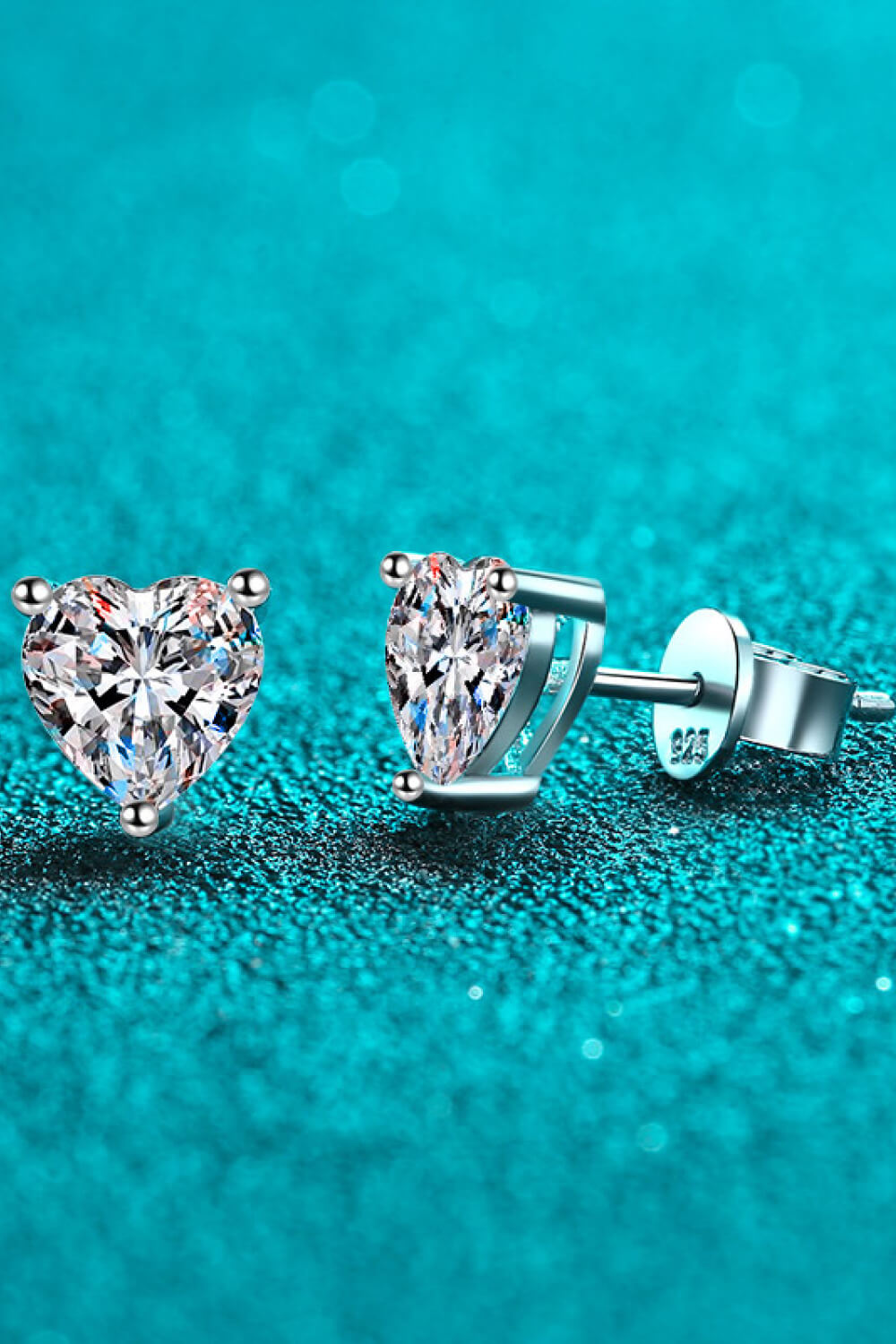 Silver heart-cut moissanite stud earrings with a sparkling diamond-like center.