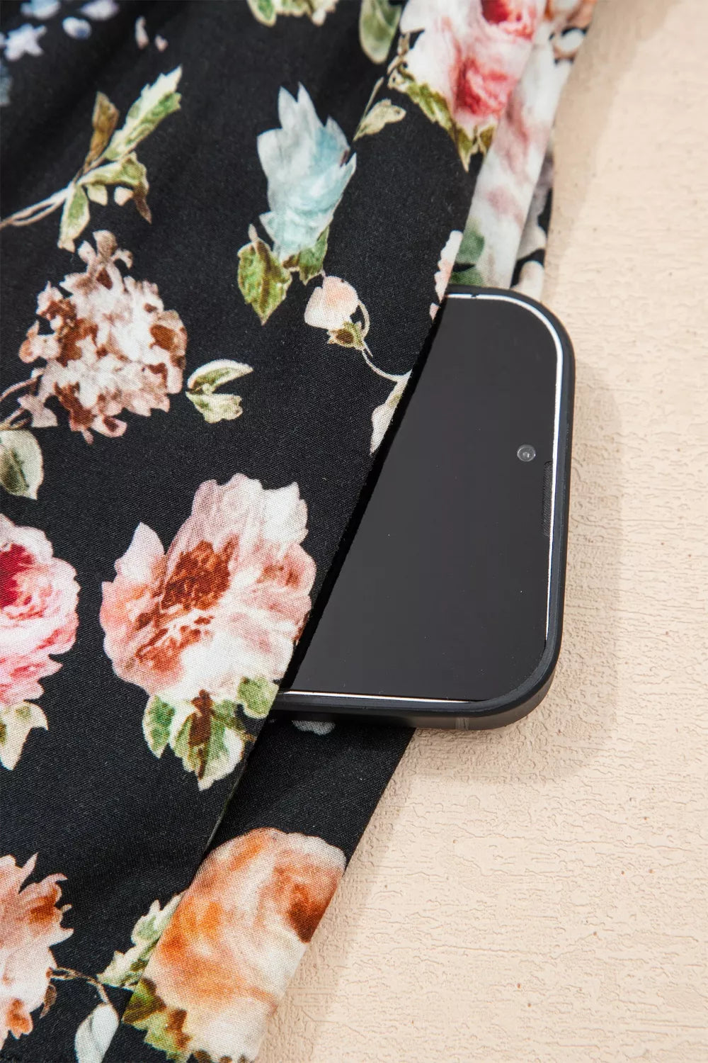 Floral maxi dress with smocked waist and side pocket detail, featuring a black background with pink and peach roses.