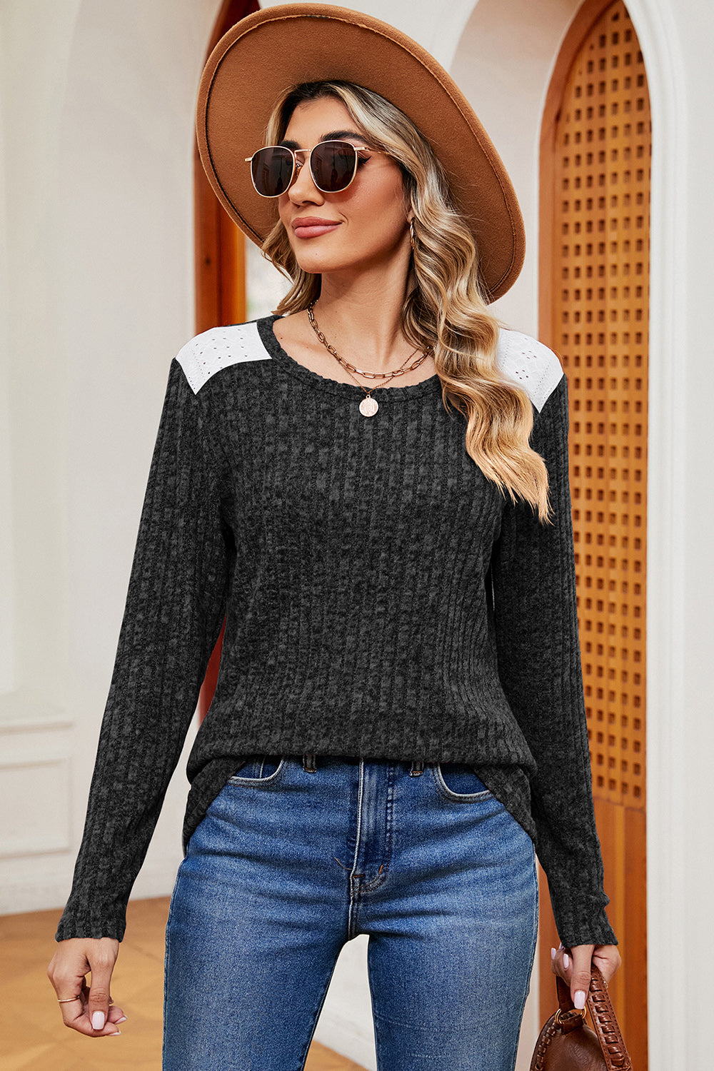 Black ribbed knit top with eyelet shoulder detail and crew neck.