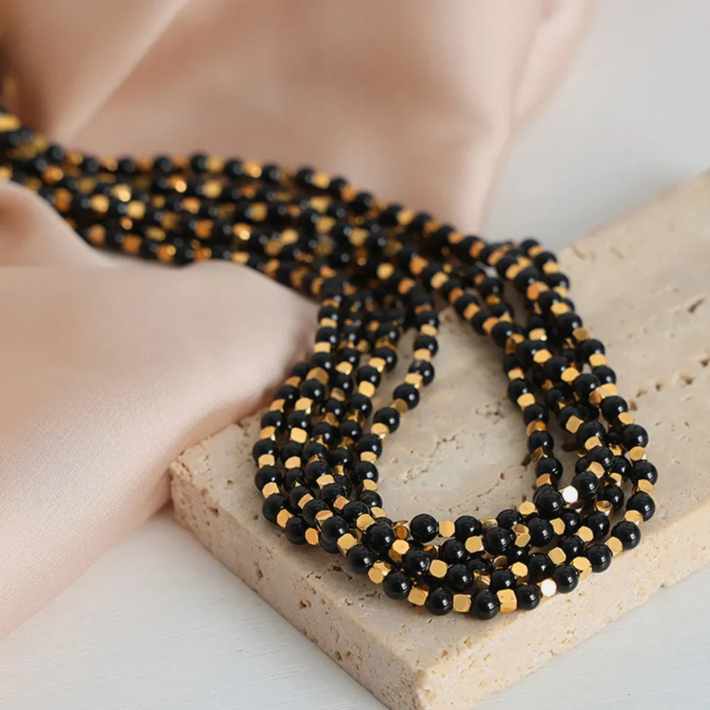 Black onyx and gold bead necklace with multiple strands.