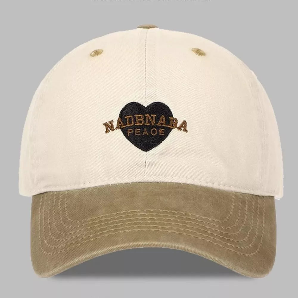 Vintage-washed baseball cap in tan and cream with embroidered heart detail.