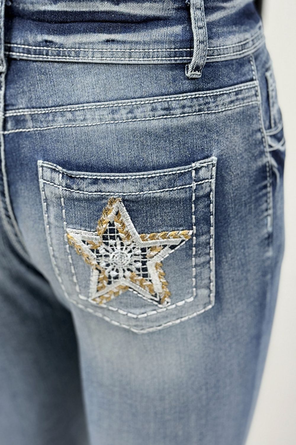 Light wash bootcut jeans with embroidered star detail on the back pocket.