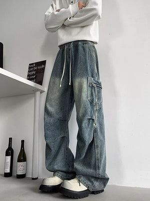 Relaxed fit blue denim cargo jeans with drawstring waist and zippered pocket detail.