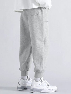 Men's grey relaxed fit sweatpants with cuffed ankles and two front pockets.