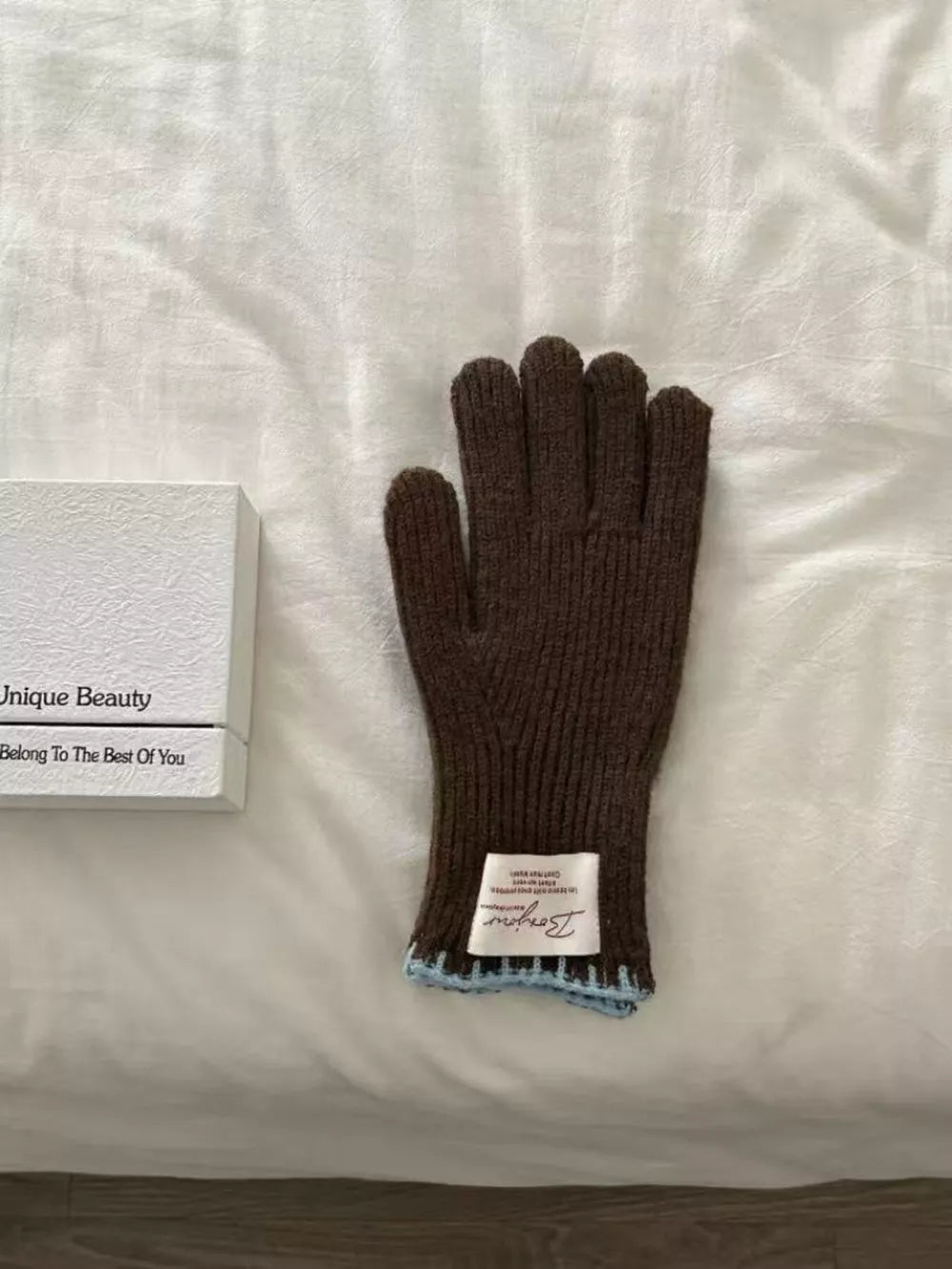Brown ribbed knit gloves with scalloped blue cuff detail and white label