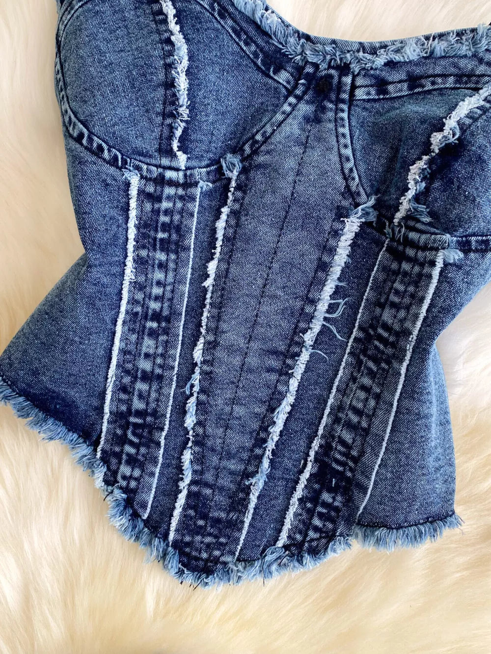Denim cami top with raw hem and vertical seam details.