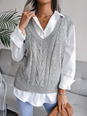 Light gray openwork cable knit vest with V-neck, styled over a white button-down shirt.