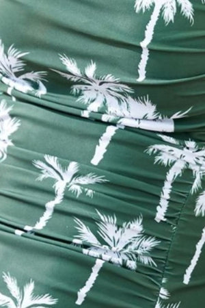 Dark green one-piece swimsuit with white palm tree print and ruching detail.