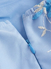Blue mini dress with floral embroidery and tie shoulder detail, featuring a side zipper.