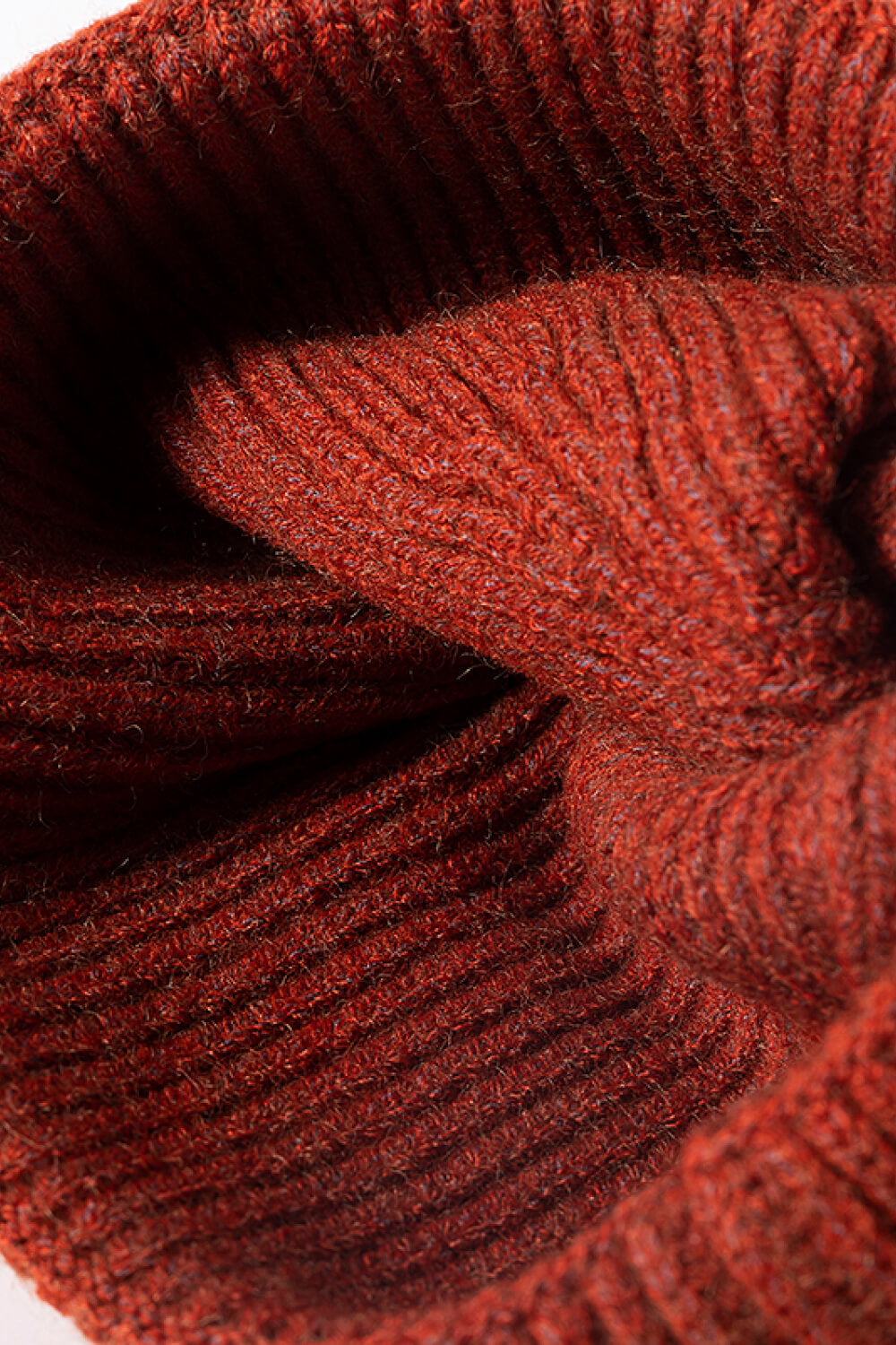 Ribbed acrylic beanie in rust color, showing texture detail.
