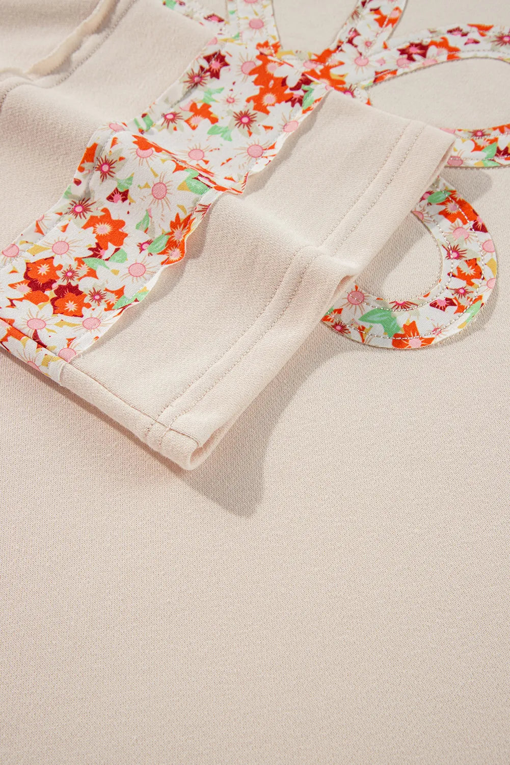 Ivory sweatshirt with floral appliqué raglan sleeves and crew neck detail.