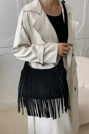 Black suede crescent crossbody bag with long fringe detail.