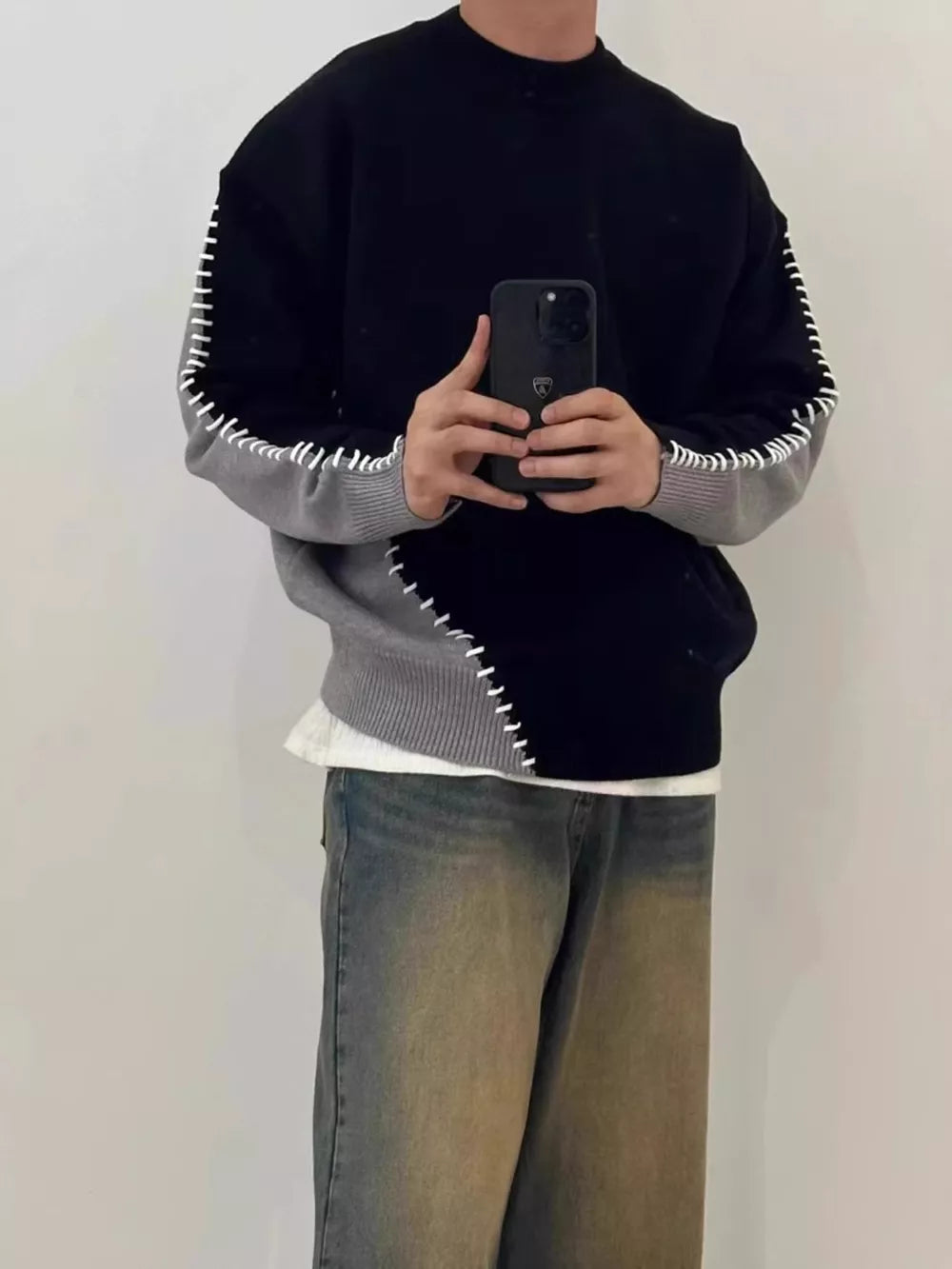 Men's black and gray two-tone mock neck sweater with contrast stitching detail.