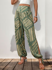 Moss green palazzo trousers with abstract print, smocked waist, and ankle ties.