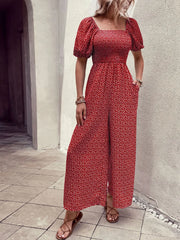 Red floral smocked bodice jumpsuit with puff sleeves and wide legs.