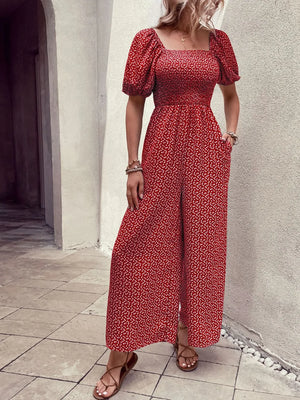 Red floral smocked bodice jumpsuit with puff sleeves and wide legs.