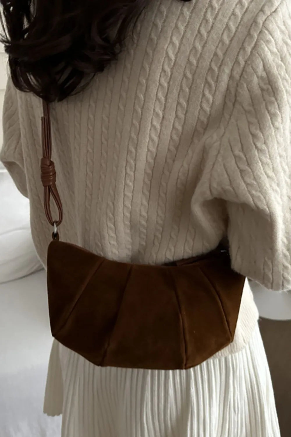 Pleated suede crescent shoulder bag in brown with a knotted strap detail.