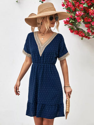Navy Swiss dot mini dress with V-neck, lace trim, and ruffled hem.