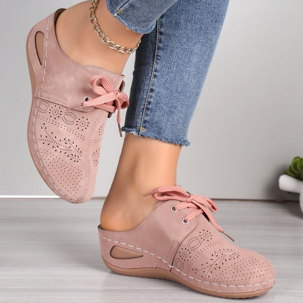 Pink perforated slip-on mules with lace-up detail and open back.