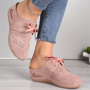 Pink perforated slip-on mules with lace-up detail and open back.