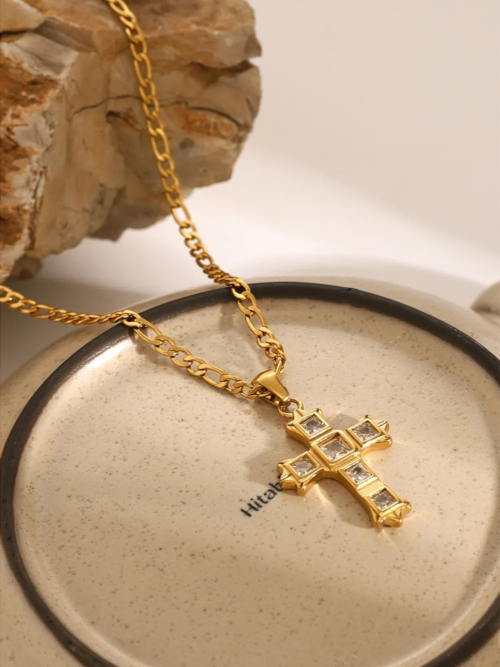 Gold cross pendant necklace with clear zirconia stones on a figaro chain.
