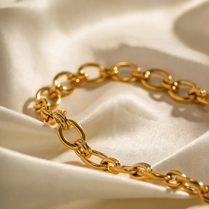 Chunky gold link collar necklace on satin fabric.