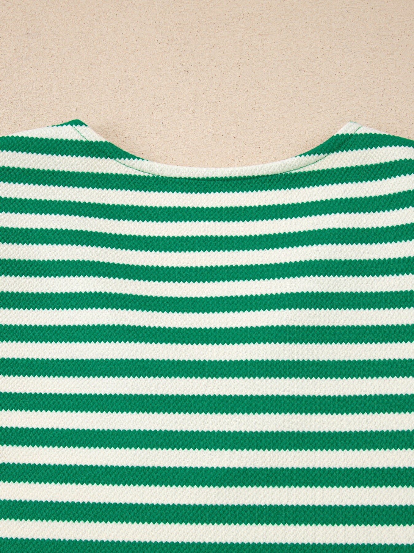 Green and white striped sweater with a V-neck and textured fabric.