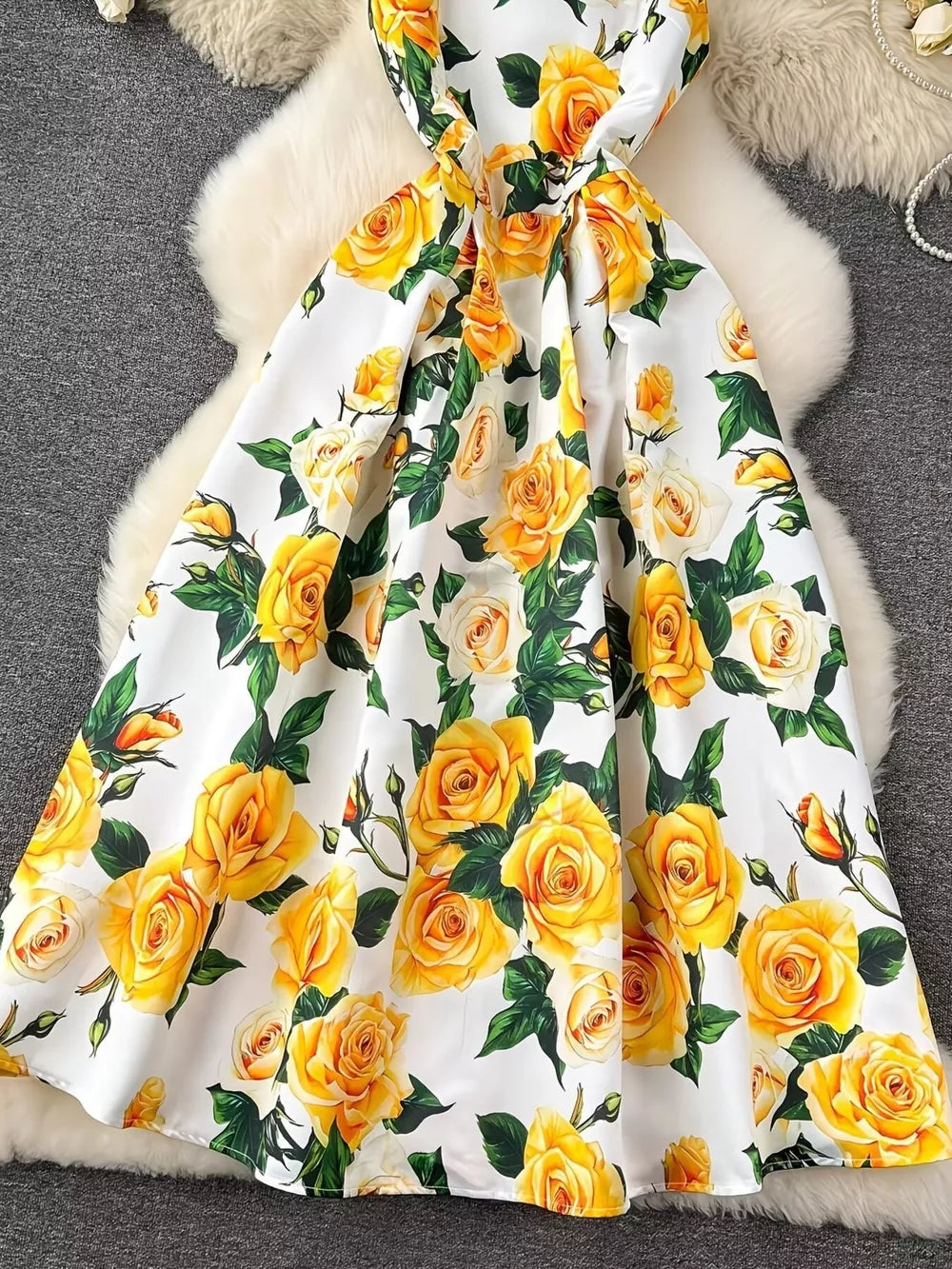 Yellow floral midi dress with a pleated skirt and a bow detail.