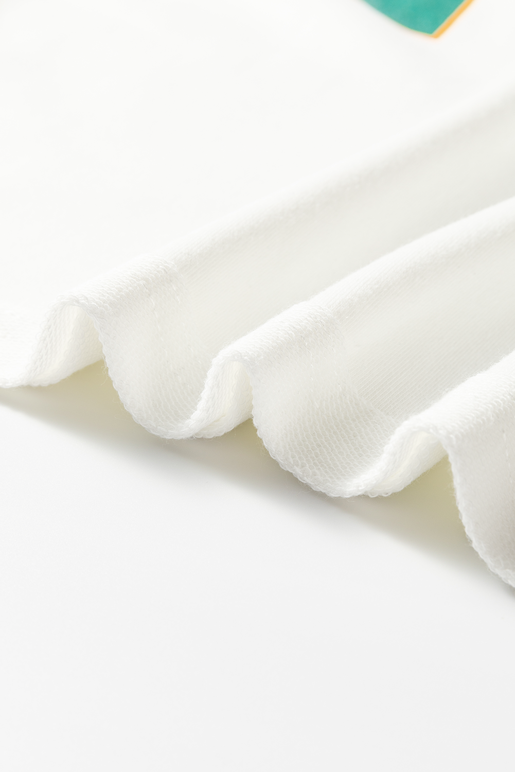White raglan sleeve sweatshirt fabric detail, showing textured knit and soft drape.