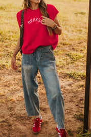 Red crew neck sweater vest with white embroidered text, styled with wide leg jeans.