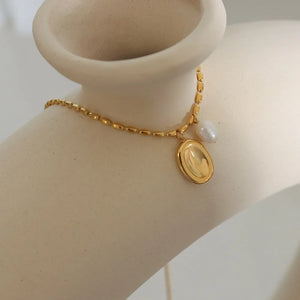 Gold oval medallion and pearl accent necklace with a delicate chain.