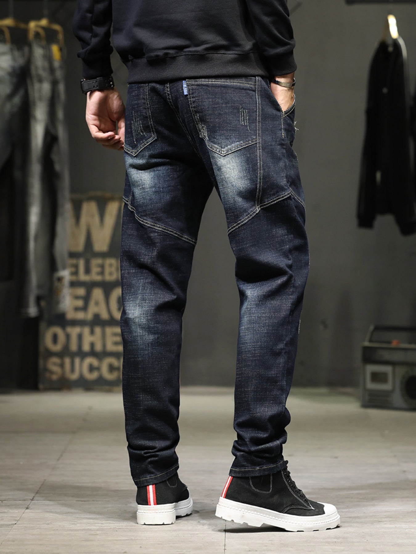 Men's dark wash distressed denim jeans with slim fit and unique paneling.