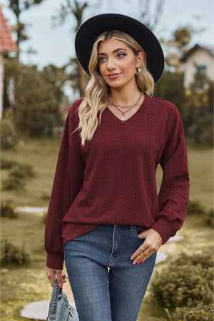 Burgundy textured cable knit V-neck sweater with long sleeves.