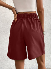Burgundy pleated front bermuda shorts with elastic waistband and side pockets.