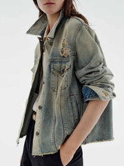 Distressed blue denim trucker jacket with button-up front and frayed hem.