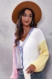 Panelled ribbed knit cardigan in pastel pink, lavender, white, and yellow with V-neck and button front.