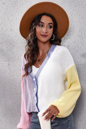 Panelled ribbed knit cardigan in pastel pink, lavender, white, and yellow with V-neck and button front.