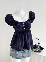 Navy polka dot maternity blouse with puff sleeves, square neckline, and decorative buttons.