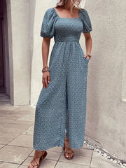 Smocked bodice floral wide-leg jumpsuit in dusty blue with puff sleeves and square neckline.