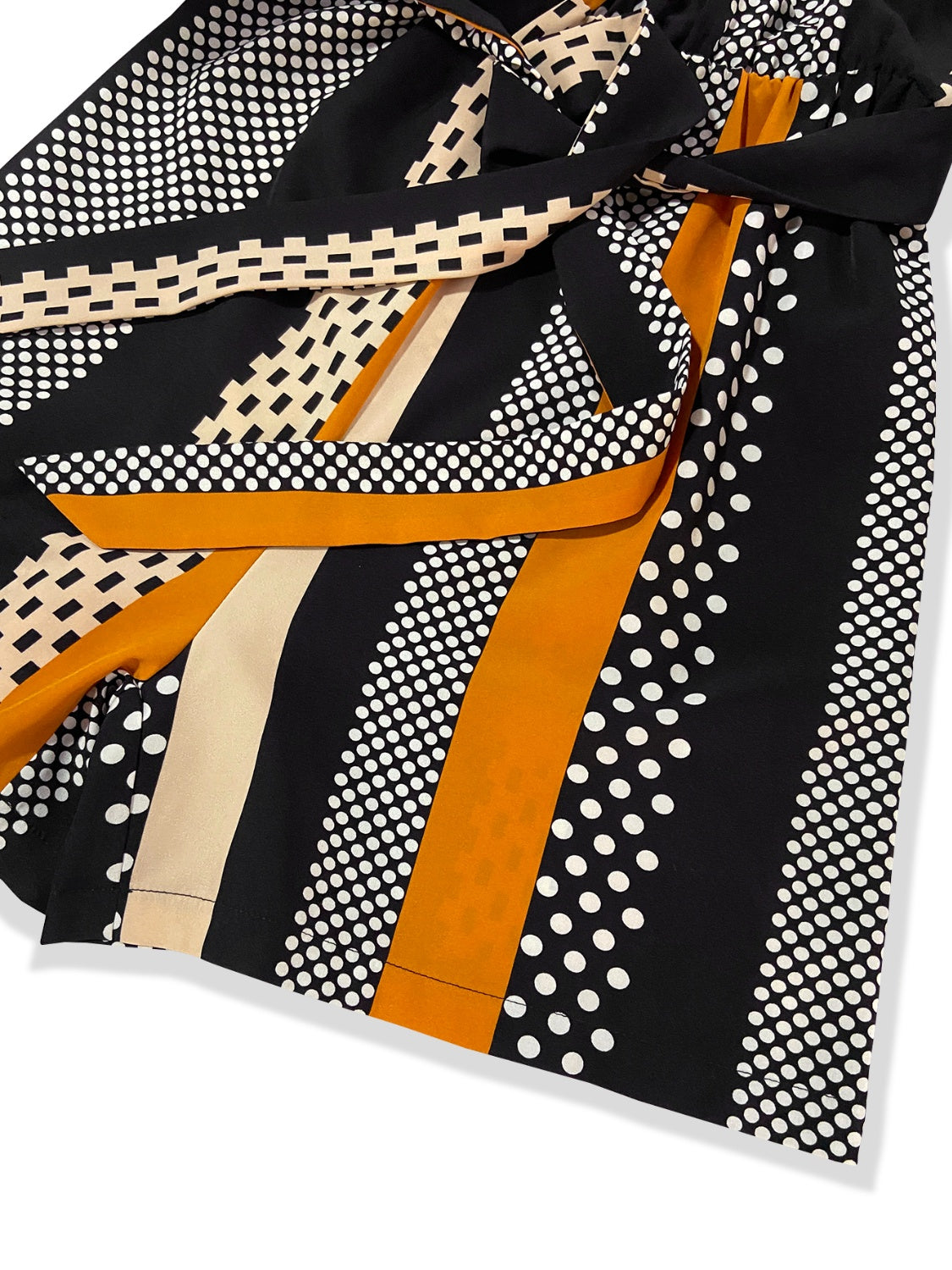 Black belted romper with polka dot and stripe patterns and a sash tie detail.