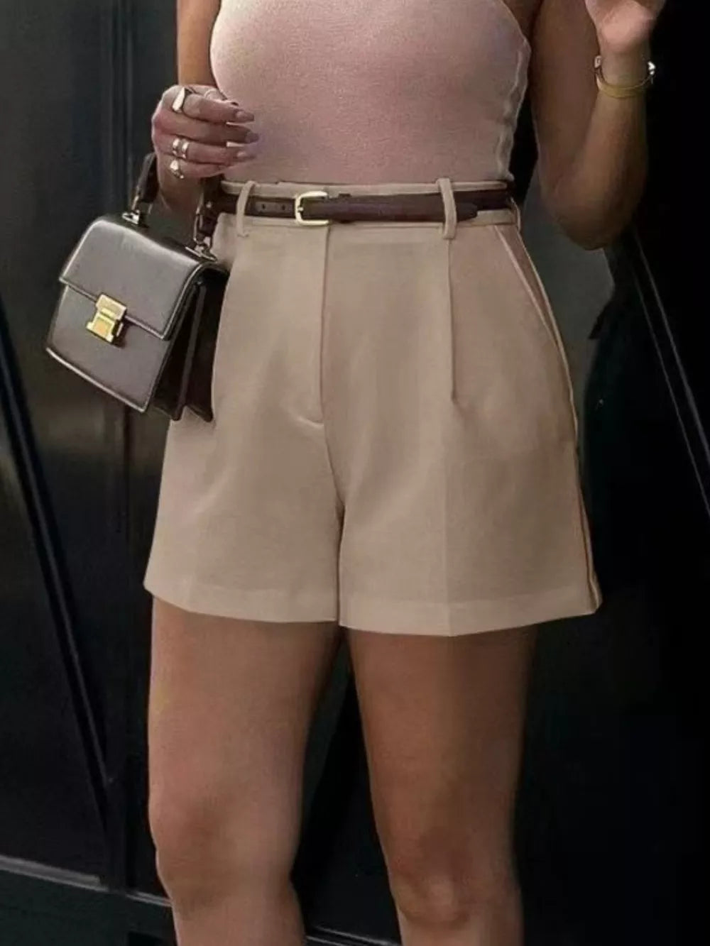 Khaki high-waisted shorts with pleats and a brown belt.