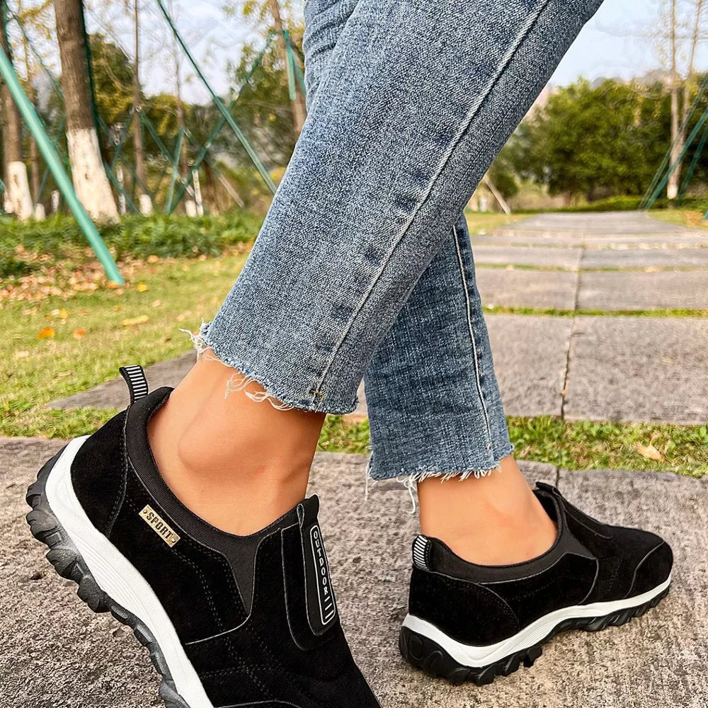 Black suede-like slip-on sneakers with white soles and "Sport" and "Outdoor" details.