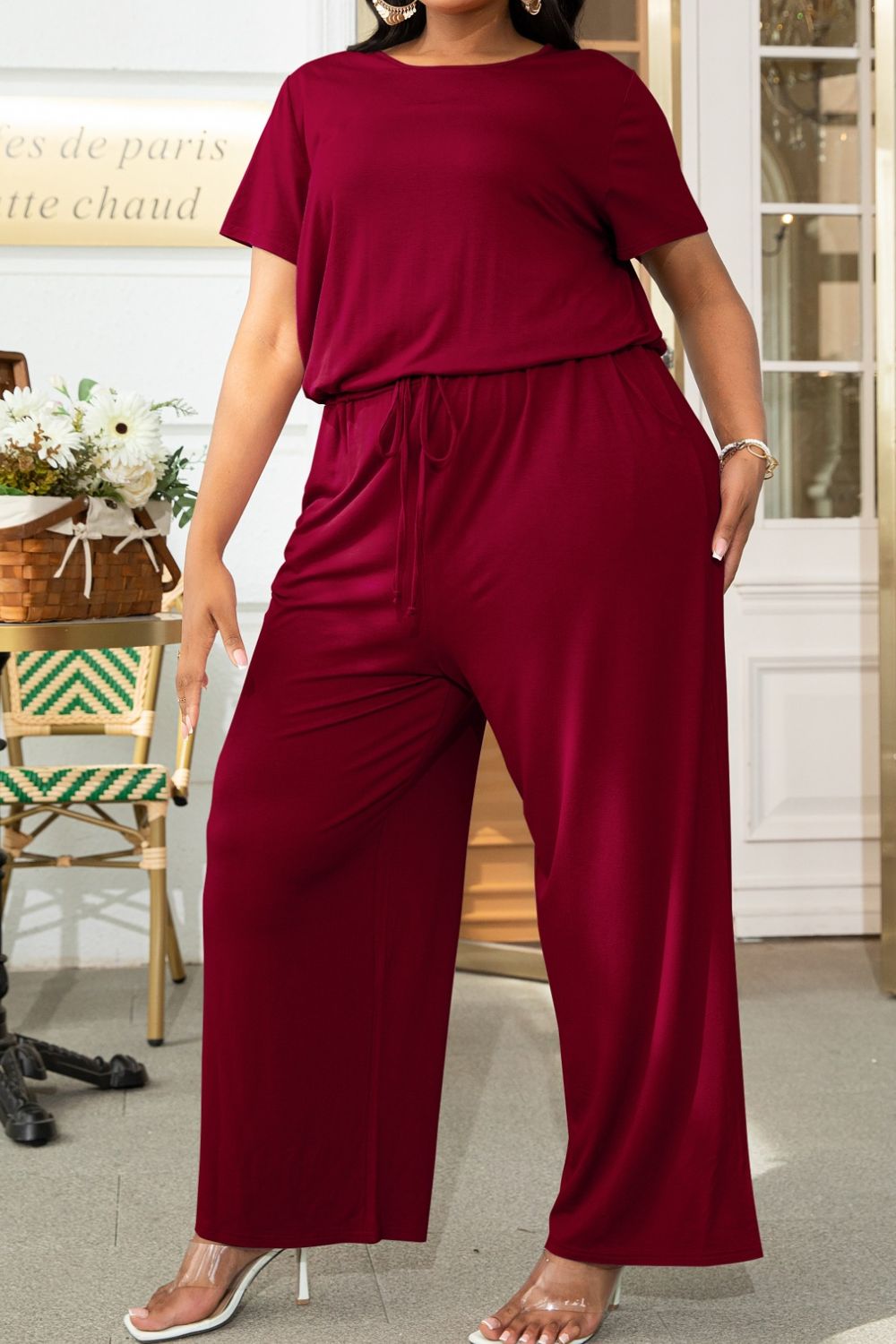 Wine relaxed fit jumpsuit with short sleeves, drawstring waist, and wide legs.