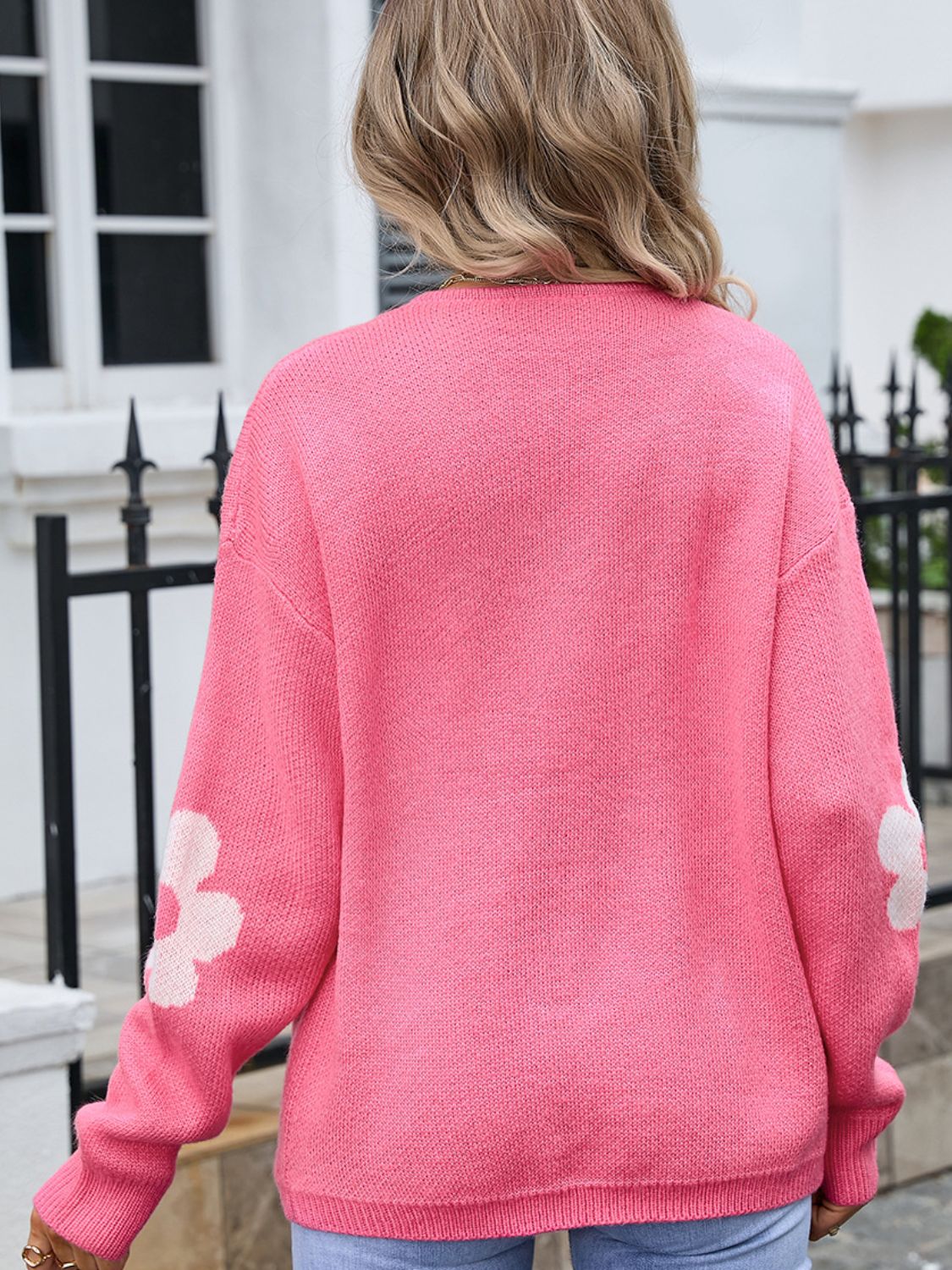 Blush pink acrylic intarsia knit cardigan with white floral details on sleeves.