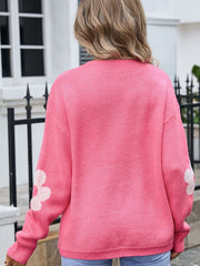 Blush pink acrylic intarsia knit cardigan with white floral details on sleeves.