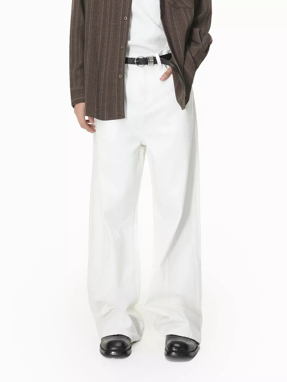 White wide leg jeans for men, cotton, with a black belt and brown striped shirt.