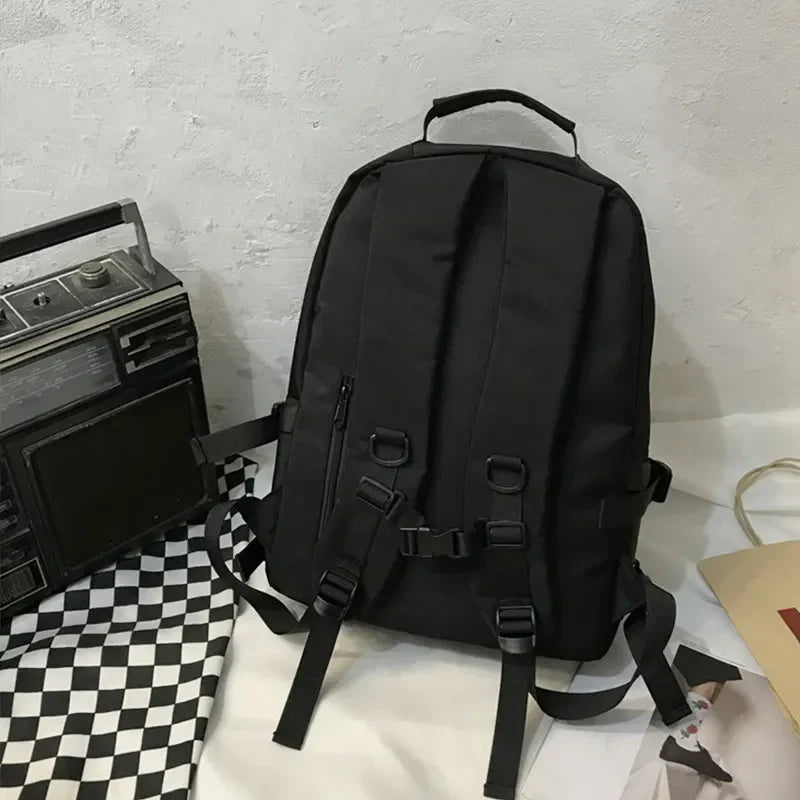 Black utility buckle backpack with adjustable straps and zipper details.