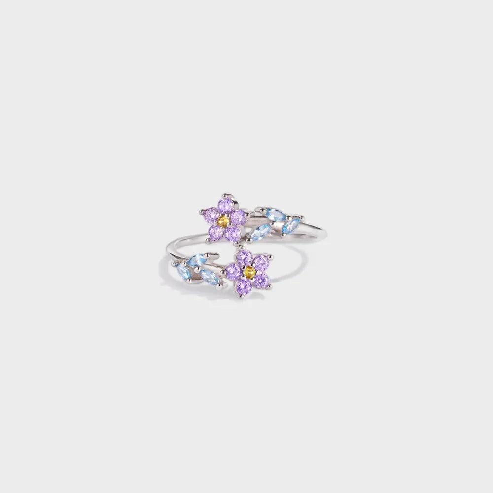 Silver ring with purple floral bypass design and blue leaf accents.