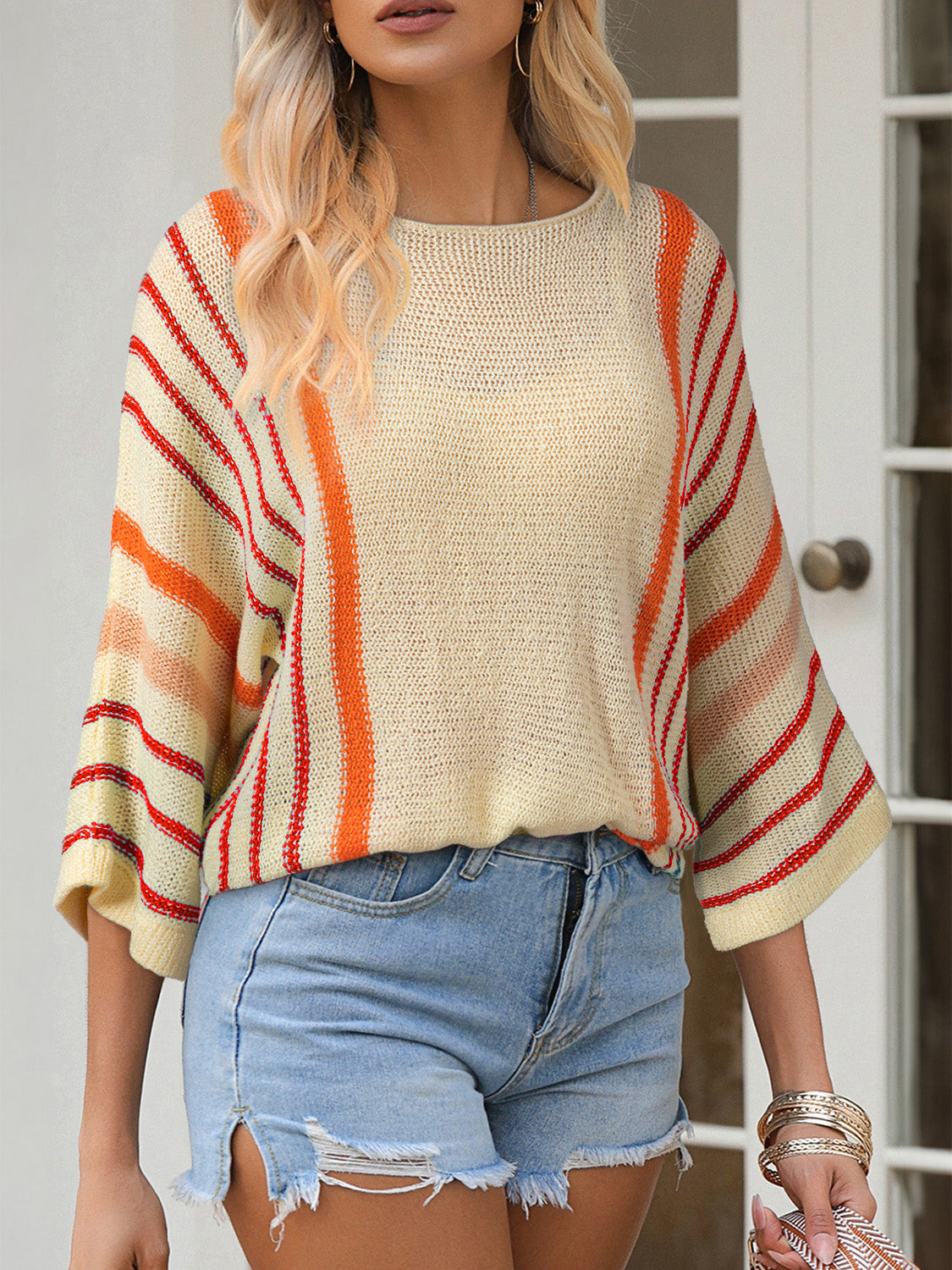 Colorblock sleeve knit pullover with orange and red stripes on a cream background.